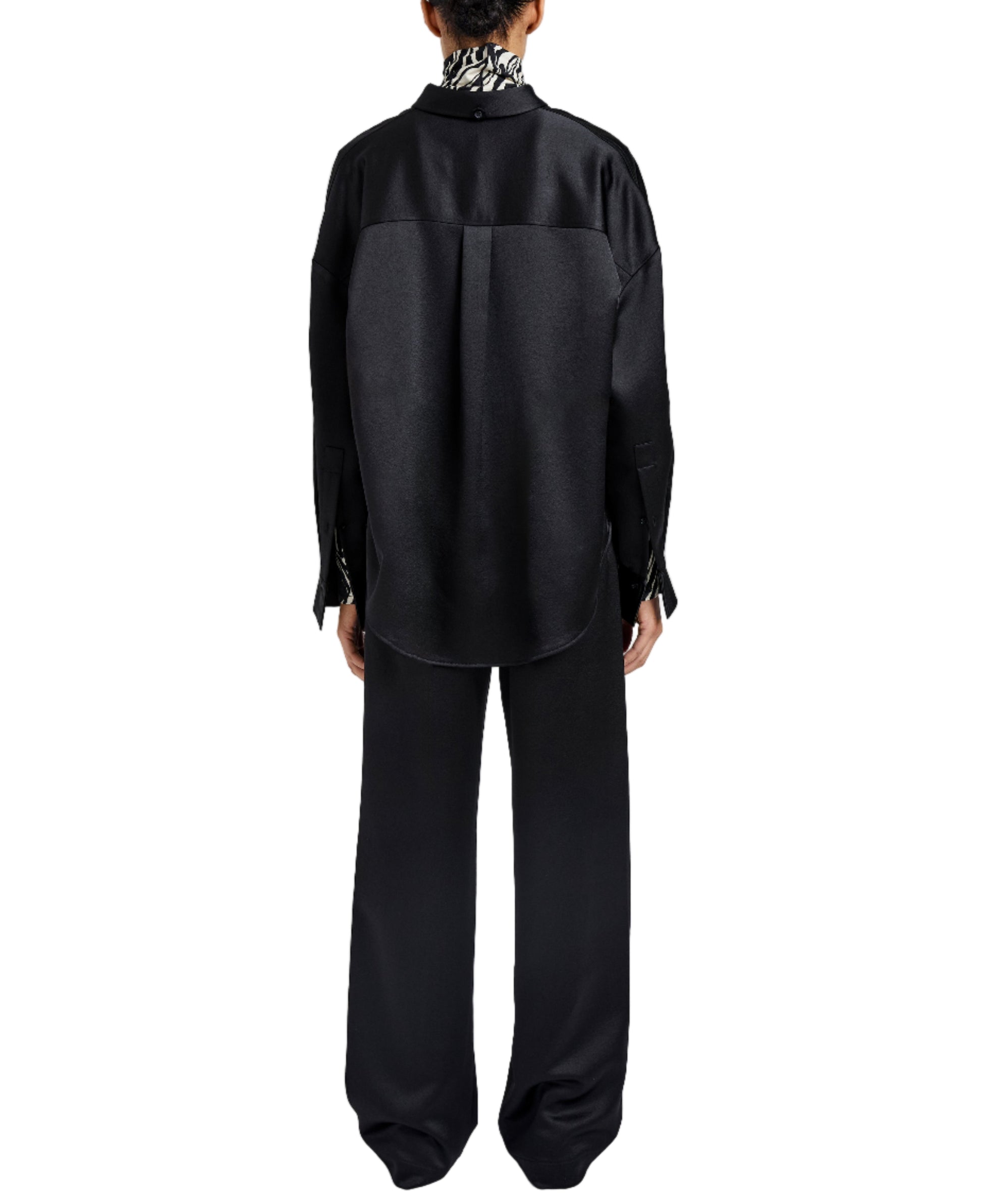 A person stands with their back to the camera, wearing the loose-fitting Caroline Crinkled Crepe Shirt and matching black wide-leg pants by Proenza Schouler White Label, highlighting a relaxed silhouette against a white background.
