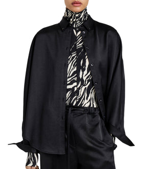 A person wears the Proenza Schouler White Label Caroline Crinkled Crepe Shirt in a relaxed fit—black, loose, and buttoned over a zebra print turtleneck—paired with matching black trousers.