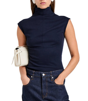 A woman wears the Proenza Schouler White Label Zane Brushed Rib Top in navy with dark jeans, hands in pockets, and a white handbag under her arm.
