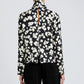 Person wearing the Ansel Top by Proenza Schouler White Label, a black long-sleeve with a white abstract floral print and vertical back slit, paired with black pants.