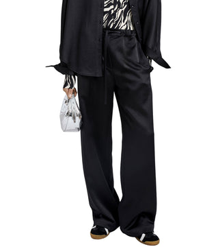 Wearing Proenza Schouler White Label Magnus Crinkled Crepe Pant, a black shirt, zebra print top, black sneakers, and holding a small silver handbag.