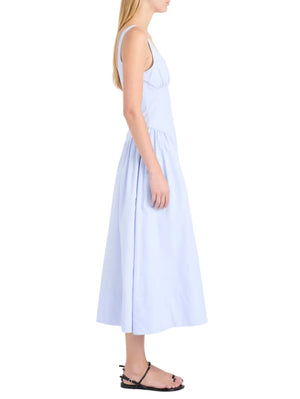 Woman in profile wears the sleeveless light blue Proenza Schouler White Label Kendall Dress with a scoop neckline, crafted from soft Tech Cotton, styled with black sandals against a white background.