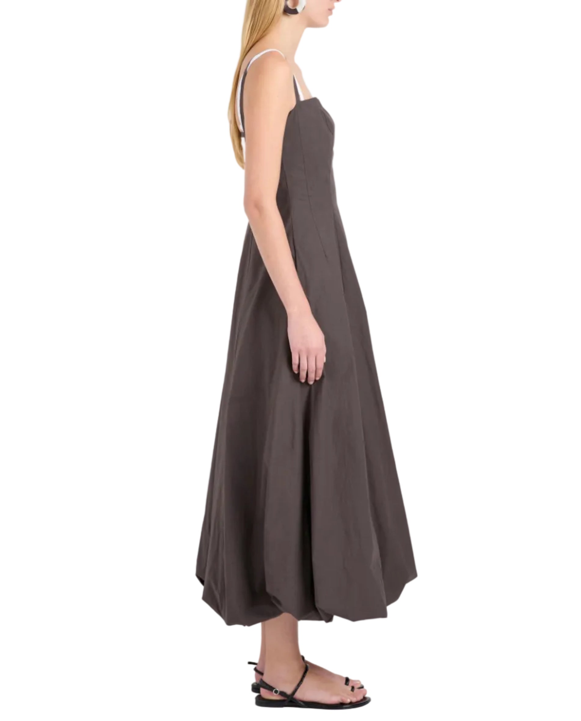 A woman stands in profile wearing the Proenza Schouler White Label Ella Dress in rumpled cotton with a fit-and-flare silhouette and thin straps, paired with black flat sandals, set against a white background.