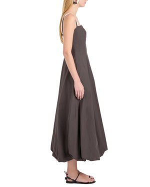 A woman stands in profile wearing the Proenza Schouler White Label Ella Dress in rumpled cotton with a fit-and-flare silhouette and thin straps, paired with black flat sandals, set against a white background.