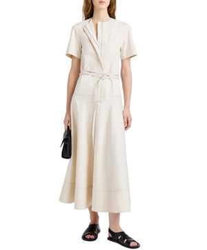 Woman in a short-sleeve cream Proenza Schouler White Label Elizabeth Dress with tie belt, styled with black sandals and a small black bag, standing against a white background.