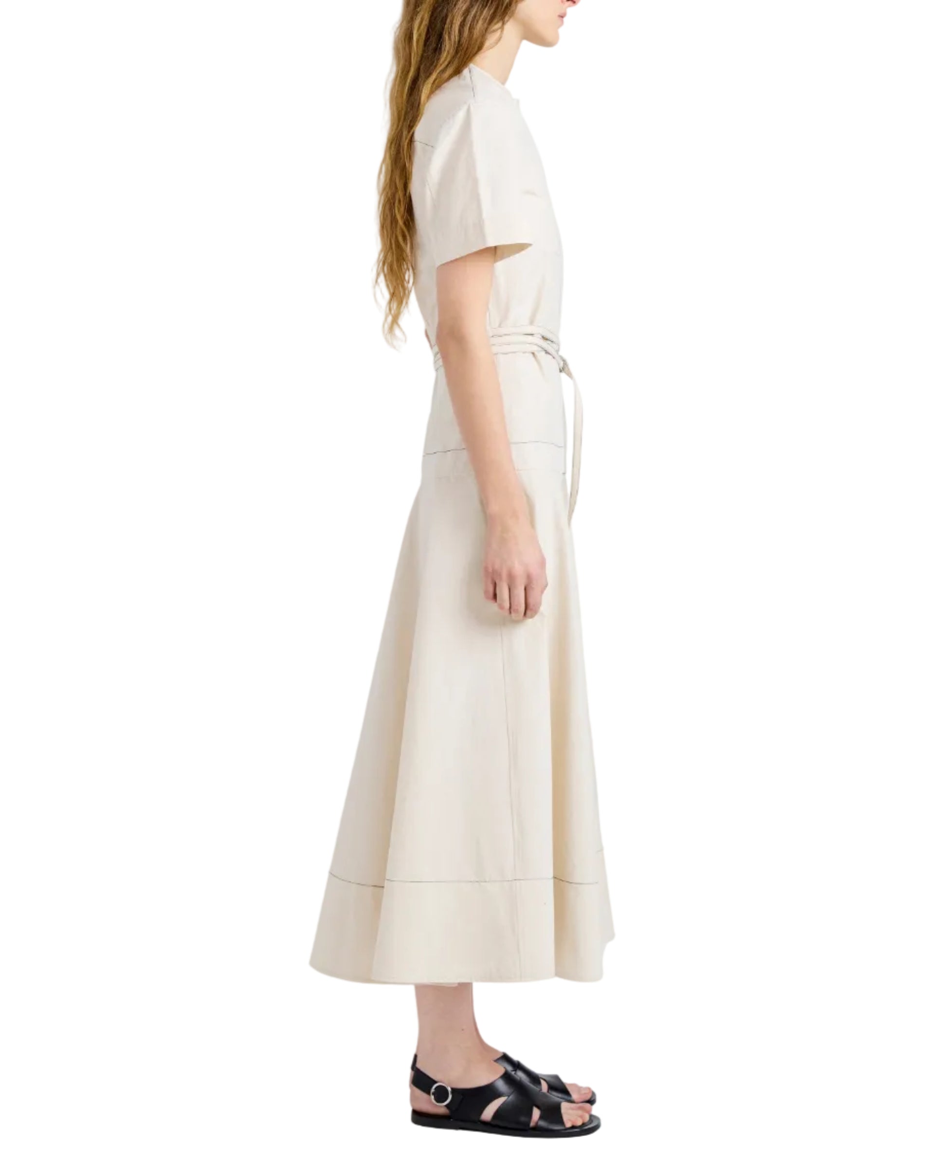 Woman in a short-sleeve, belted Elizabeth Dress by Proenza Schouler White Label, crafted from cream cotton linen with a fit-and-flare silhouette, paired with black sandals and standing in profile against a white background.