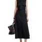 A person wears the Proenza Schouler White Label Anoushka Dress—sleeveless, black with an abstract brushstroke print—paired with black sandals and carrying a large black handbag by their side.