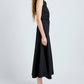 A woman stands in profile wearing the Proenza Schouler White Label Anoushka Dress, a sleeveless black midi poplin dress, paired with black flat sandals against a plain light background.