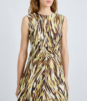 A woman wears the Anoushka Dress by Proenza Schouler White Label, a sleeveless poplin dress with yellow, brown, and black abstract brushstroke print, standing against a plain light background.
