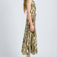 A woman stands in profile against a plain background, wearing the Proenza Schouler White Label Anoushka Dress, a sleeveless A-line style with a multicolored abstract print, paired with black sandals.