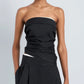 A person wearing the Maisy Strapless Top by Proenza Schouler White Label with black high-waisted pants, standing against a plain light gray background.