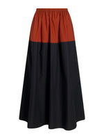 The Nyla Skirt by Proenza Schouler White Label is an A-line poplin skirt with color-blocking, featuring a rust-colored top, black lower section, and an elastic waistband.
