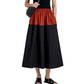 A person wears the Proenza Schouler White Label Nyla Skirt, a color-blocked black and red midi, paired with a sleeveless black top, black sandals, and a black crossbody bag against a white background.
