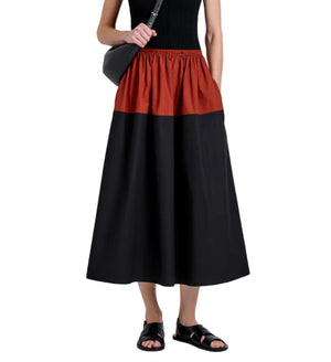 A person wears the Proenza Schouler White Label Nyla Skirt, a color-blocked black and red midi, paired with a sleeveless black top, black sandals, and a black crossbody bag against a white background.