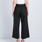 A person stands with their back to the camera against a plain background, wearing Proenza Schouler White Label Cropped Raver Pant in black and heeled sandals.