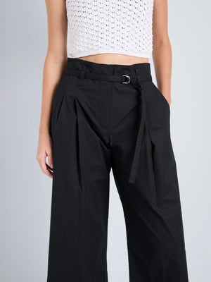 Model wears Proenza Schouler White Label Cropped Raver Pant in high-rise black with belt detail and a white crochet sleeveless crop top, posed against a plain background.