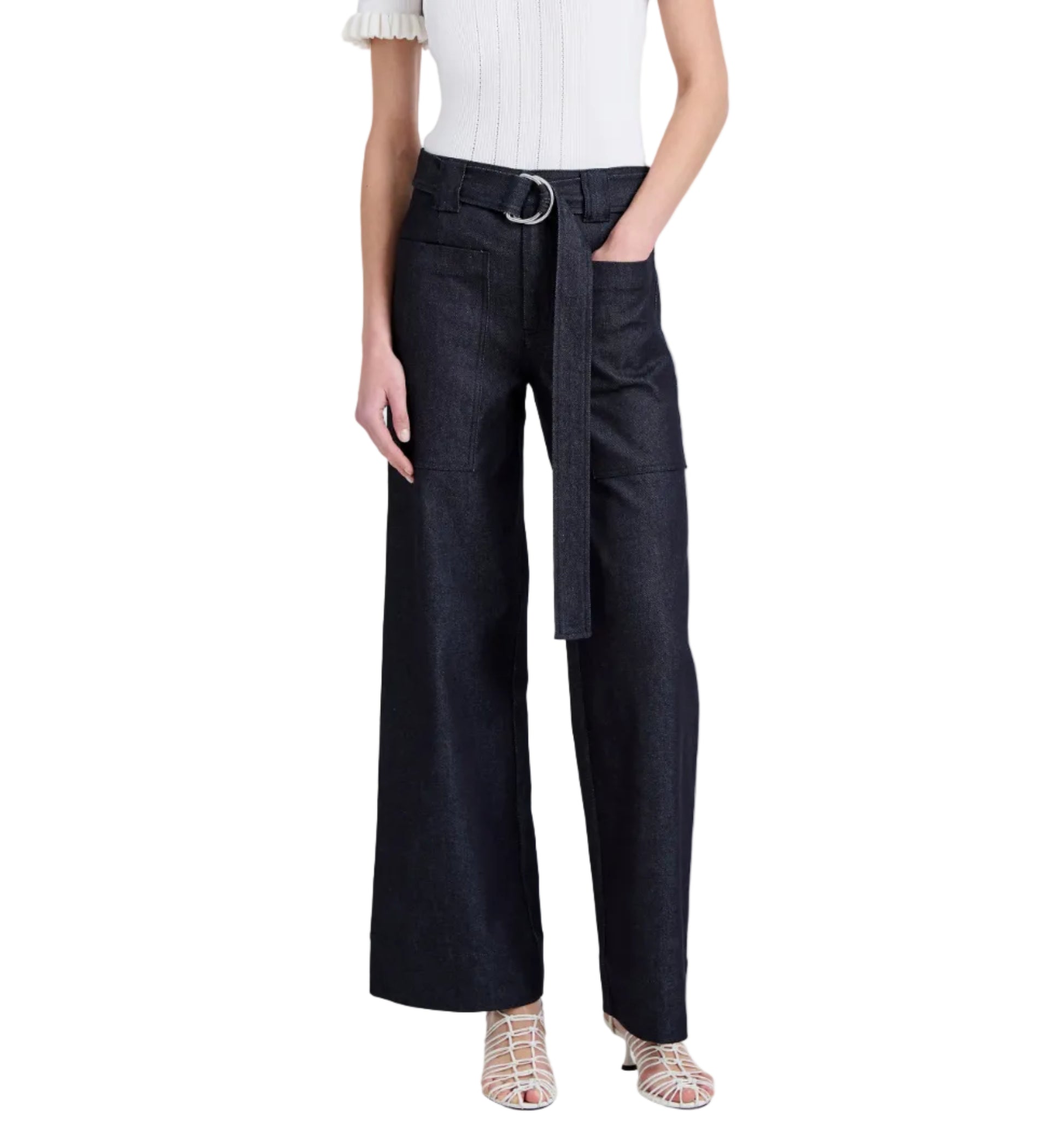 Wearing the Proenza Schouler White Label Lina Pant—a high-waisted, wide-leg dark denim style with adjustable belt—paired with a white short-sleeve top and white strappy sandals.