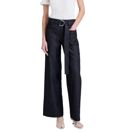 Wearing the Proenza Schouler White Label Lina Pant—a high-waisted, wide-leg dark denim style with adjustable belt—paired with a white short-sleeve top and white strappy sandals.