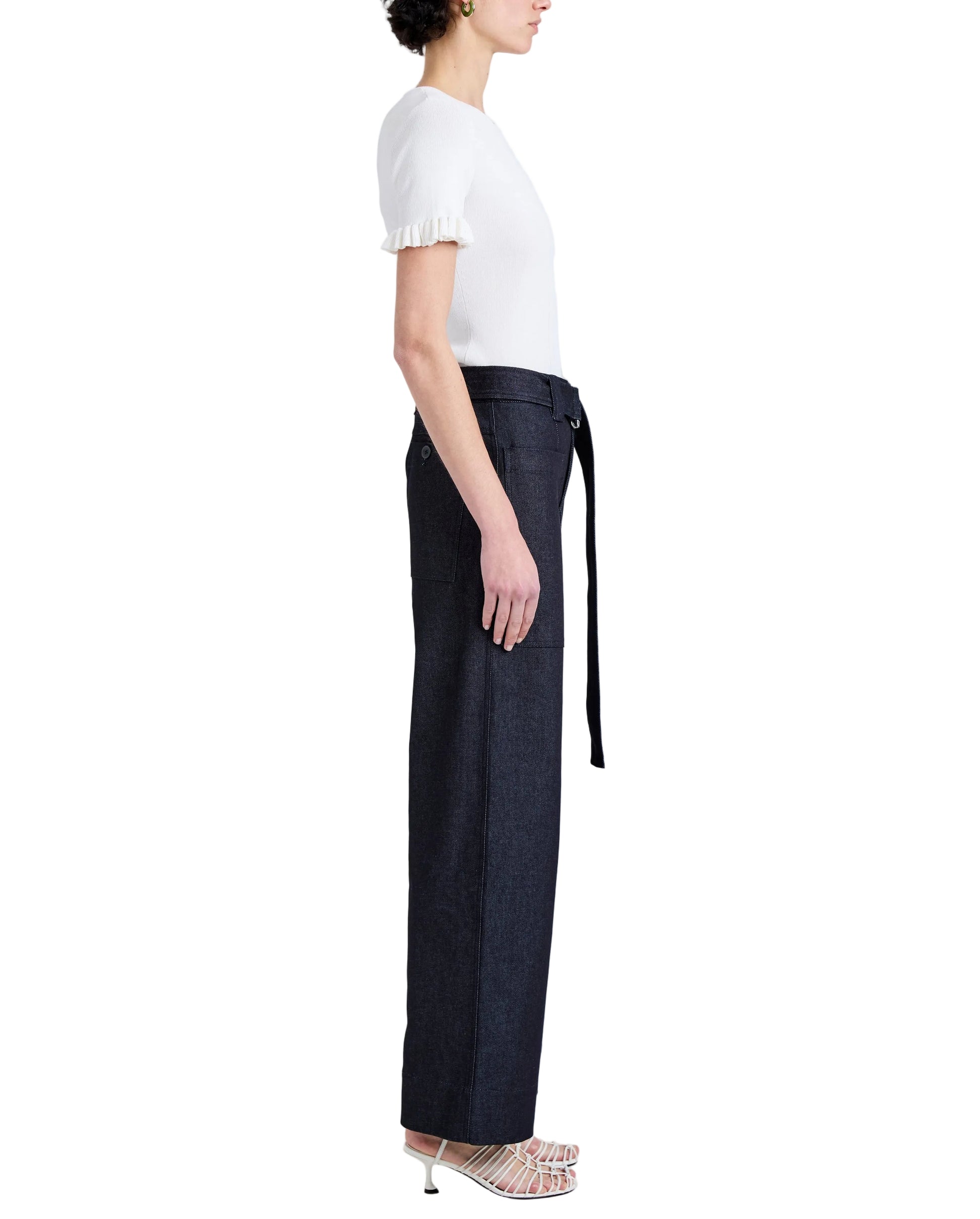 Model in profile wears Proenza Schouler White Label Lina Pant—a high-waisted, stretch twill wide-leg style with adjustable belt—paired with a white short-sleeve top and open-toe heels against a white background.