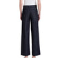 A person, seen from the back, wears a short-sleeve white top and Proenza Schouler White Label Lina Pant—high-waisted, wide-leg dark denim jeans—paired with white heeled shoes.