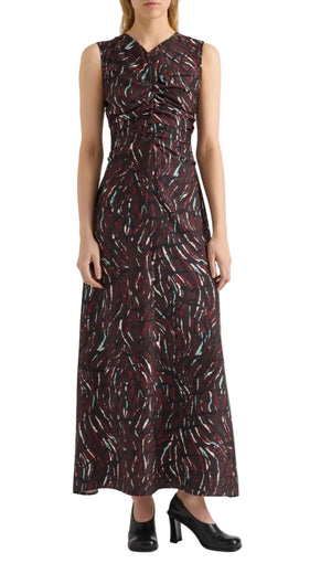 A woman wearing the Clem Dress by Proenza Schouler White Label—a sleeveless, fitted, ankle-length dress crafted from printed soft twill with a swirling red, white, and teal pattern—pairs it with black heeled shoes while standing against a white background.