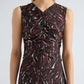 A woman wears the Clem Dress by Proenza Schouler White Label, a sleeveless, printed soft twill dress designed with gathered fabric at the chest and waist. The dress showcases red, white, and teal abstract streaks against a dark background.