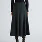 A person is shown from the back against a plain background, wearing the Proenza Schouler White Label Heidi Stretch Cotton Skirt in dark green, styled with a black textured long-sleeve top and black knee-high boots.