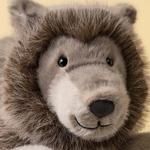 Close-up of Jellycat’s Ulrich Wolf, a gray stuffed animal with black eyes, fluffy fur, and a stitched smile against a plain background.