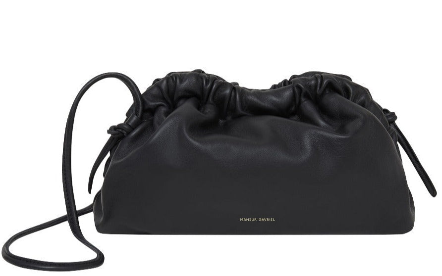 A Mansur Gavriel Mini Cloud Clutch made from luxurious Italian lamb leather, featuring a drawstring top closure and a versatile multi-function strap.