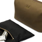 The Bennett Winch Canvas Wash Bag, distinguished by its brown canvas exterior and embroidered logo, is equipped with a durable YKK brass zipper. Next to it, a black zippered pouch holding a silver grooming tool is elegantly displayed on a white surface.