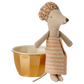 The Maileg Wellness Mouse, Big Sister - Rose, dressed in a striped towel dress and shower cap, stands next to a yellow cup with a white interior, ready for fun in her playset featuring a golden metal bathtub.