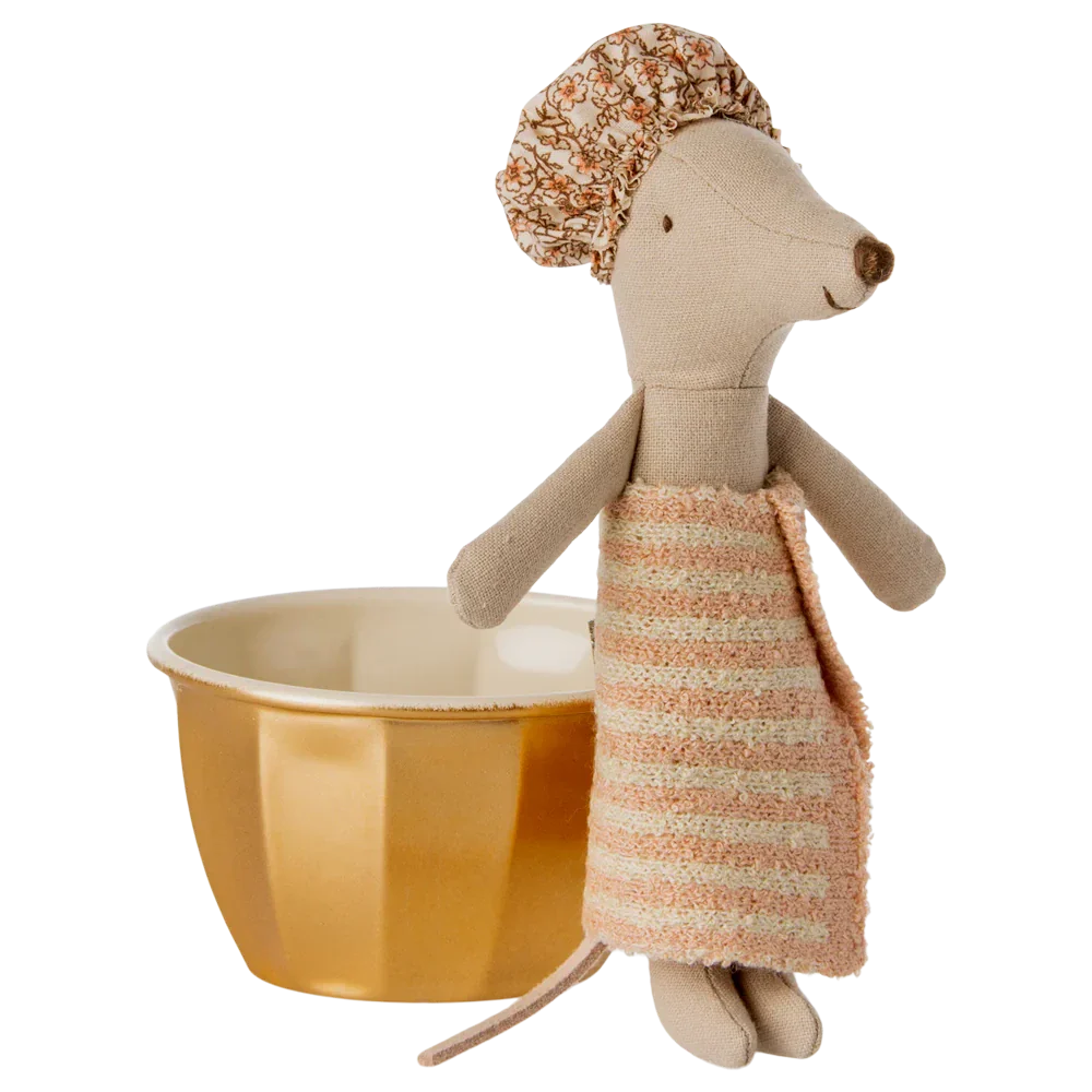 The Maileg Wellness Mouse, Big Sister - Rose, dressed in a striped towel dress and shower cap, stands next to a yellow cup with a white interior, ready for fun in her playset featuring a golden metal bathtub.