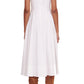 Rear view of a woman wearing a Staud Wells Dress in white, sleeveless corset-style midi dress and brown high-heeled boots, standing against a plain background.