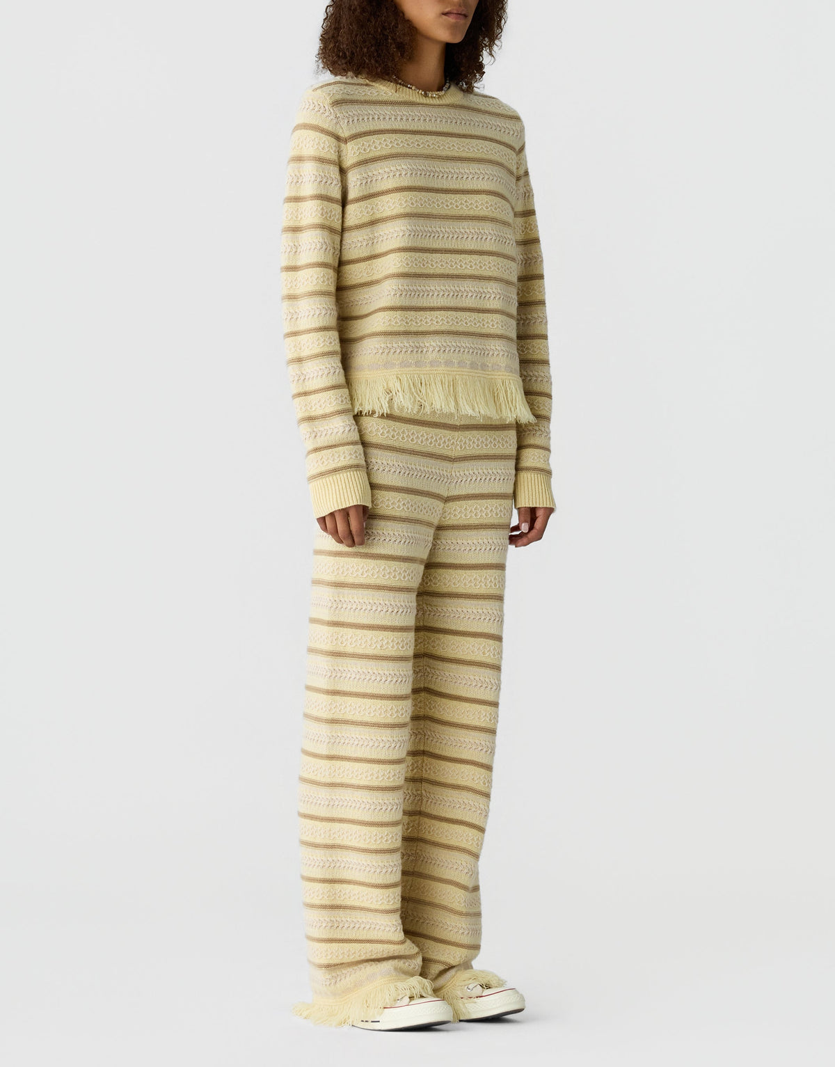 Model wears the Guest in Residence Western Stripe Crew, a cream and beige striped sweater with wide-legged pants, against a plain white background.