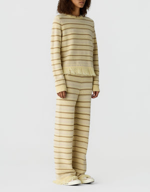 Model wears the Guest in Residence Western Stripe Crew, a cream and beige striped sweater with wide-legged pants, against a plain white background.