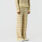 Model wearing the Western Stripe Pant by Guest in Residence, paired with a matching beige and cream striped knit sweater, against a plain white background.