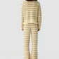 Model wearing the Western Stripe Crew by Guest in Residence, a cream and beige striped knit sweater with a fringed hem, viewed from the back against a white background.