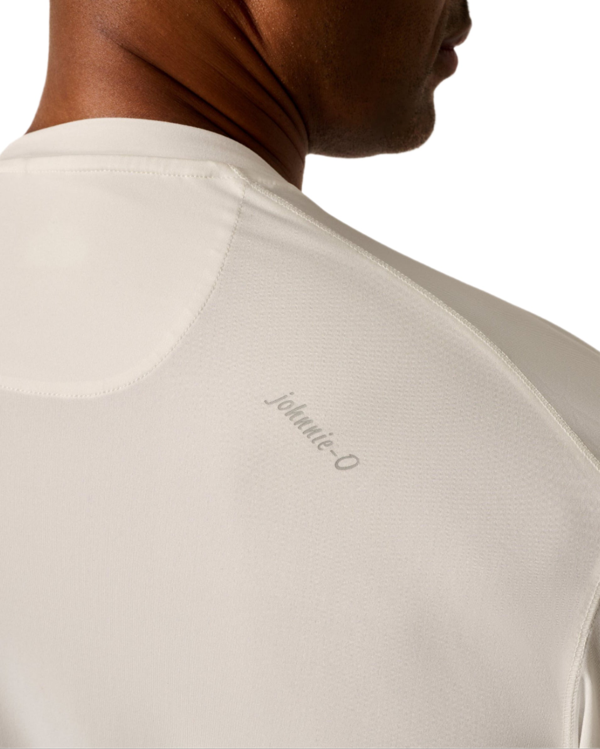 Close-up of a person wearing the Johnnie-O Basin Performance Sun Shirt in cream, featuring "Johnnie-O" text on the back near the shoulder, ideal for staying stylish even during a heat wave.