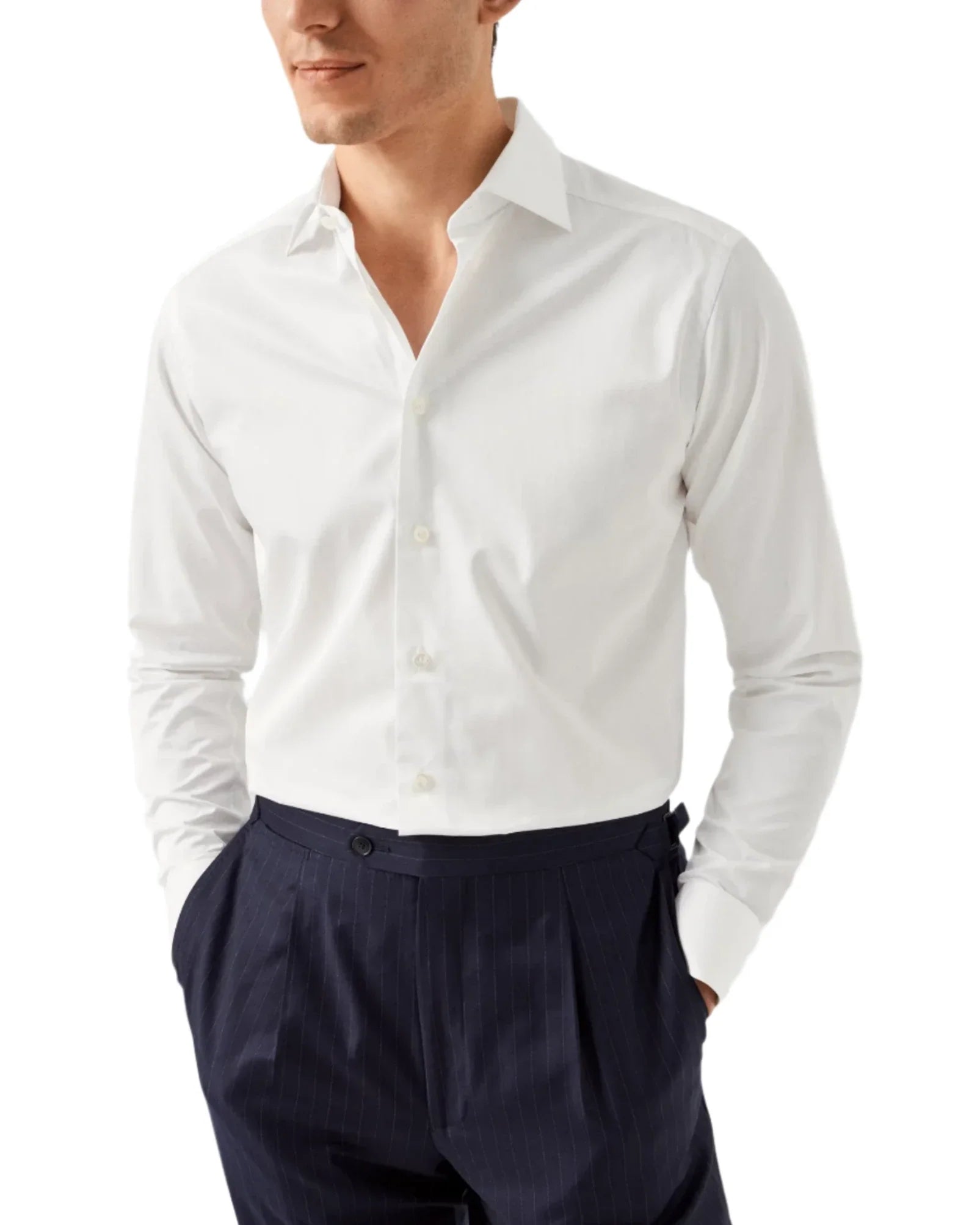 A man wearing an Eton Solid Elevated Twill Shirt, known for its crisp and crease-resistant fabric, paired with navy pinstripe pants, with his hands in his pockets.