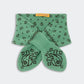 A pair of green socks featuring a black paisley pattern is folded neatly with a yellow “Guest in Residence” tag, paired with the Bandana Bowtie Scarf by Guest in Residence for a coordinated look.