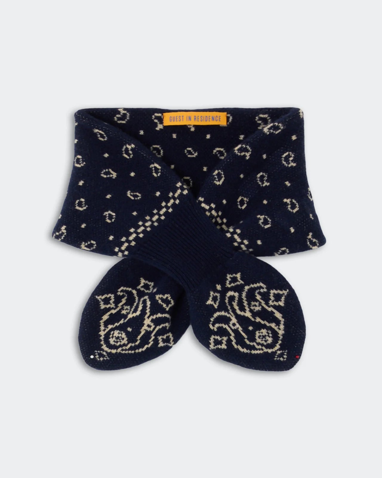 Navy blue knit socks featuring a cream paisley and dot design, neatly folded with a yellow “Guest in Residence” label on the cuff—perfectly paired with your favorite Bandana Bowtie Scarf from Guest in Residence.