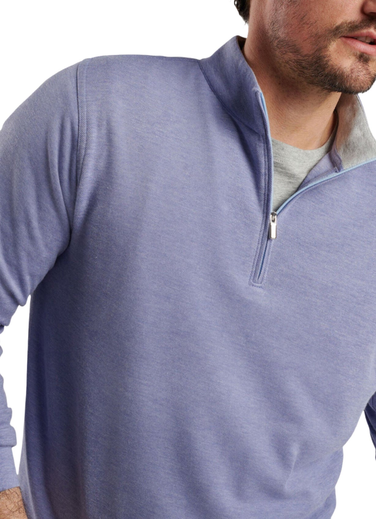 A man is wearing the Peter Millar Crown Comfort Pullover in light blue, featuring four-way stretch fabric, layered over a gray shirt.