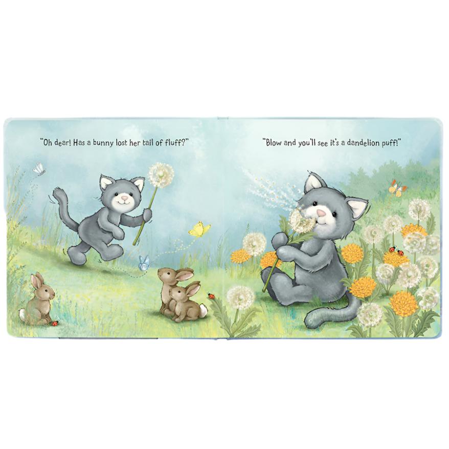 The Jellycat When I Wonder Book from Jellycat features an illustration of a grey cat holding a dandelion puff, with another cat and two rabbits nearby. This enchanting scene, perfect for a baby book, includes the text, "Oh dear! Has a bunny lost her tail of fluff?" and "Blow and you’ll see it’s a dandelion puff!" making it ideal for parent-child reading.