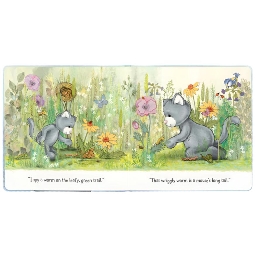 An illustrated children’s story, the "Jellycat When I Wonder Book," features a cat observing a worm in a garden. Text reads: "I spy a worm on the leafy, green trail" and "That wriggly worm is a mouse's long tail." This charming book by Jellycat is perfect for parent-child reading sessions.