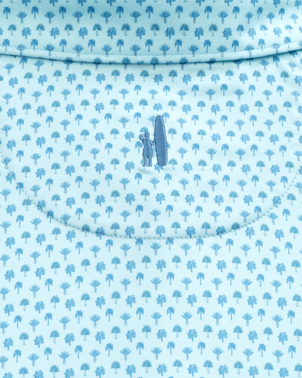 Close-up of the light blue fabric from the Johnnie-O Woods Polo by Johnnie-O, featuring a small pattern of trees and a surfing design with a figure holding a surfboard at the center. This polo is crafted with moisture-wicking properties, making it perfect for active beach days.