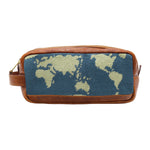 The Smathers & Branson Toiletry Bag is a rectangular brown Italian leather pouch with a woven fabric front panel, showcasing a beige world map against a blue background. Its hand-stitched needlepoint design gives it an artisanal feel, making this bag both stylish and functional.