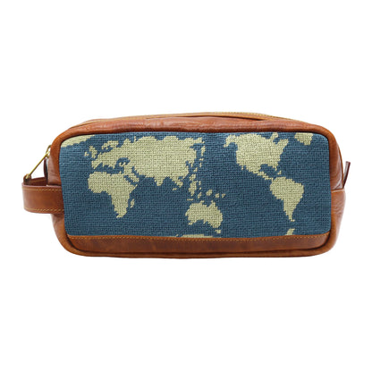 The Smathers & Branson Toiletry Bag is a rectangular brown Italian leather pouch with a woven fabric front panel, showcasing a beige world map against a blue background. Its hand-stitched needlepoint design gives it an artisanal feel, making this bag both stylish and functional.