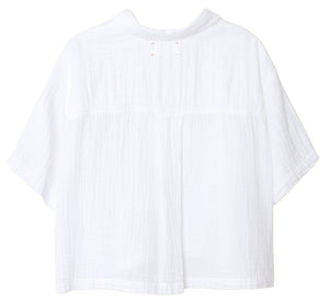 The Xirena Ansel Top, a white short-sleeve shirt with a collar, is shown from the back. This short boxy top by Xirena is meticulously crafted in Los Angeles from lightweight cotton poplin, offering a textured fabric that exudes both comfort and style.