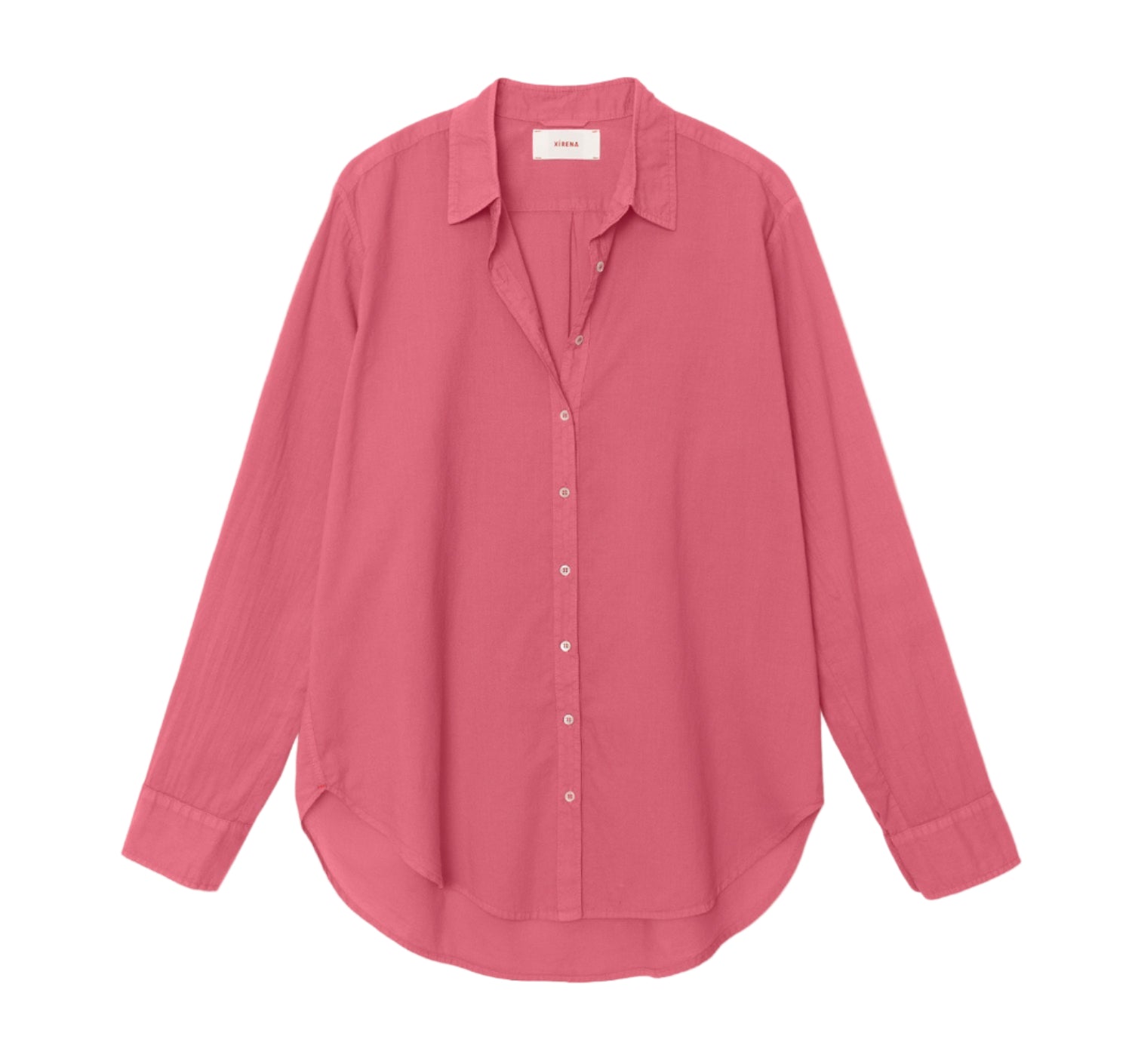 The Xirena Beau Shirt, crafted from cotton poplin in solid pink, features long sleeves, a pointed collar, and a curved hem, shown laid flat against a white background.