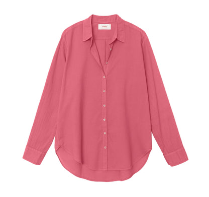 The Xirena Beau Shirt, crafted from cotton poplin in solid pink, features long sleeves, a pointed collar, and a curved hem, shown laid flat against a white background.